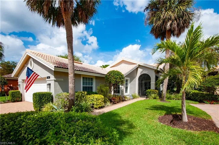 View of front facade with an attached garage, a tiled roof, decorative driveway, stucco siding, and a front yard