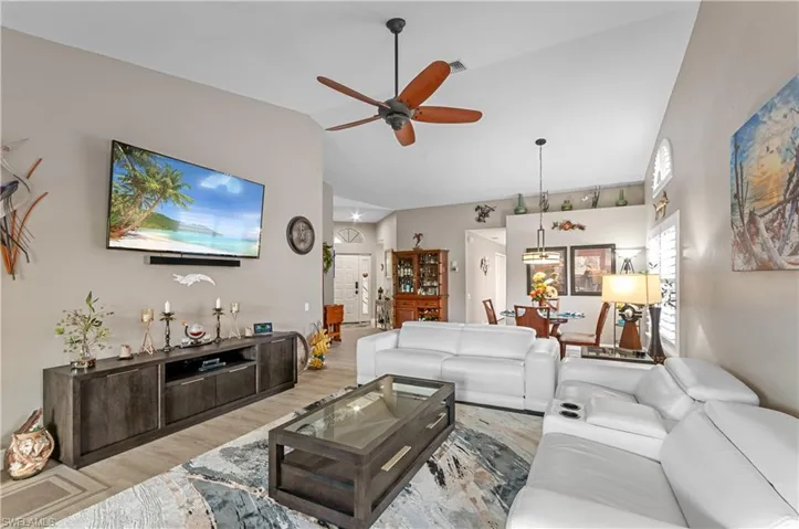 Living area featuring ceiling fan, high vaulted ceiling, wood finished floors, and visible vents