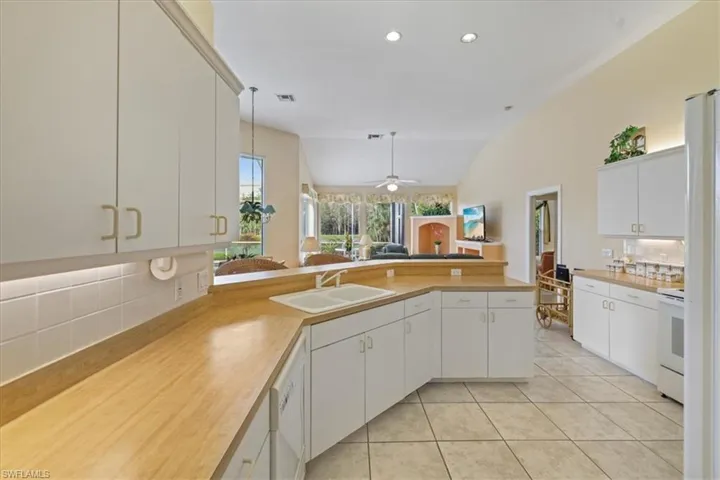 Kitchen featuring light tile patterned floors, light countertops, a sink, white appliances, and a peninsula