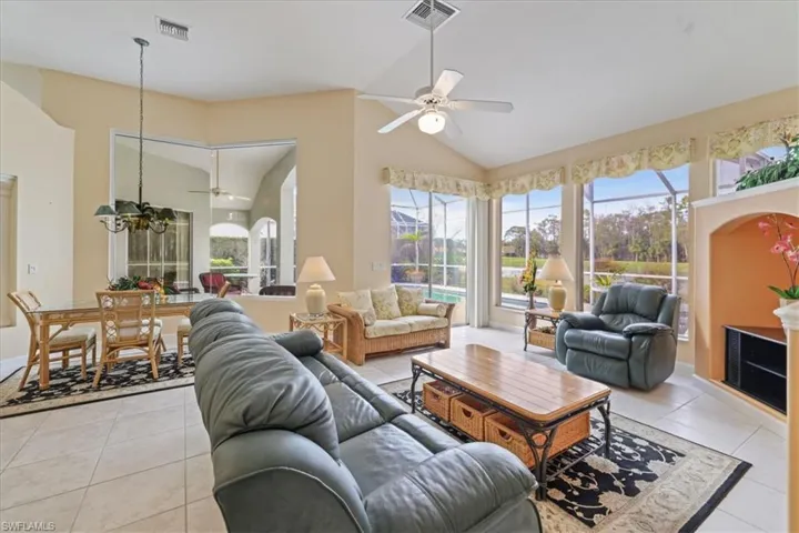 Living room with light tile patterned floors, ceiling fan with notable chandelier, and visible vents