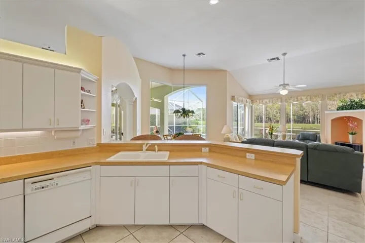 Kitchen with visible vents, open floor plan, white dishwasher, a sink, and a peninsula