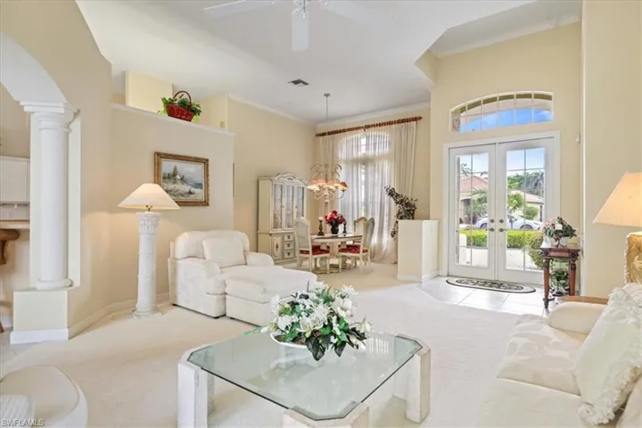 Sitting room featuring ornate columns, crown molding, visible vents, and carpet flooring