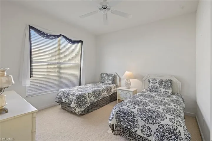 Carpeted bedroom with a ceiling fan and baseboards