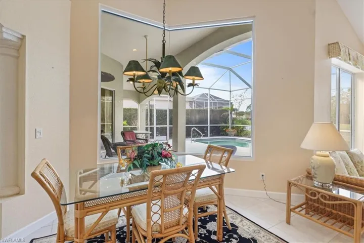 Tiled dining room featuring baseboards, a sunroom, and an inviting chandelier