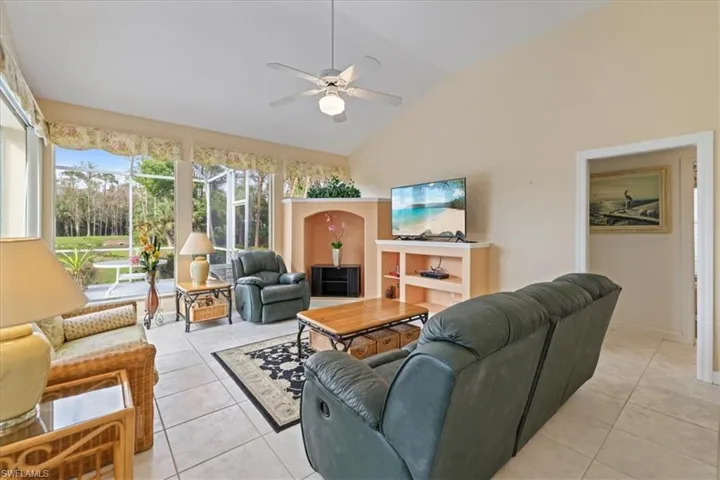 Living area with lofted ceiling, a ceiling fan, and light tile patterned flooring