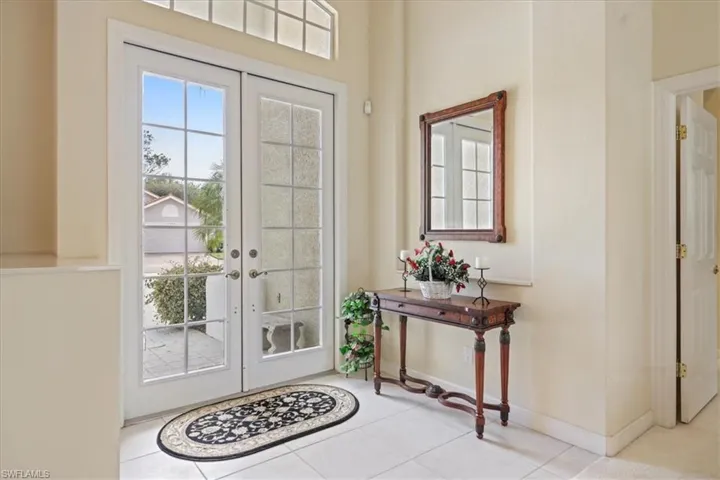 Tiled foyer with french doors and baseboards