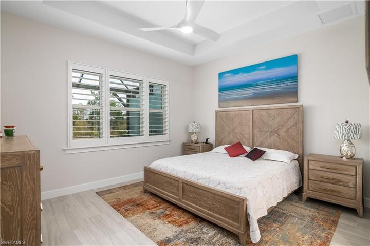 Spacious Master Bedroom with High Tray Ceilings, Fan, Plantation Shutters, Tile Flooring.