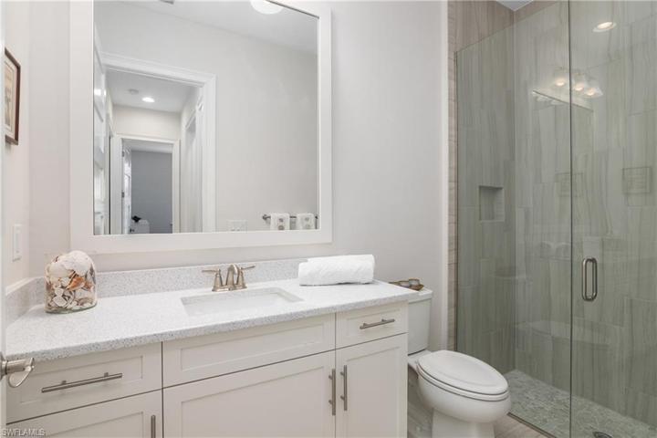 Full Bathroom 2 of 2. Quartz Tops, White Cabinetry, Framed Mirror. Walk-in Shower with Frameless Glass Door.