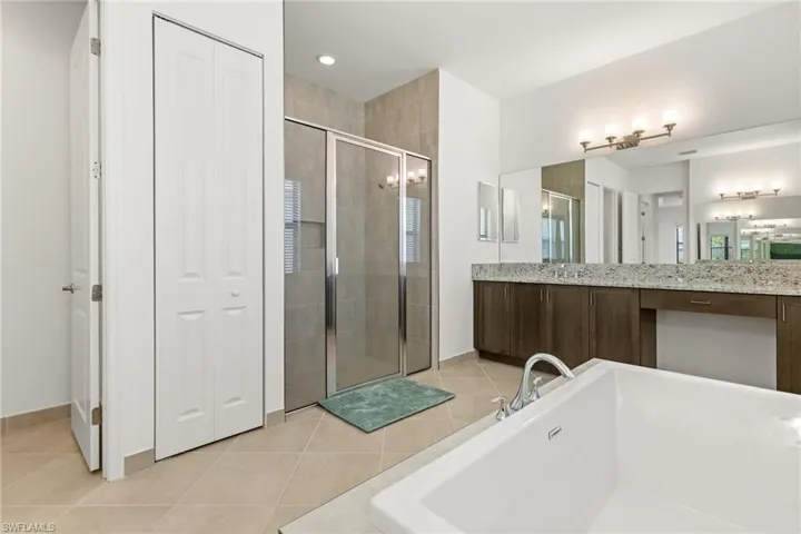 Bathroom featuring plus walk in shower, tile patterned floors, and vanity