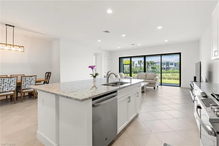 Kitchen with sink, hanging light fixtures, stainless steel dishwasher, and white cabinetry