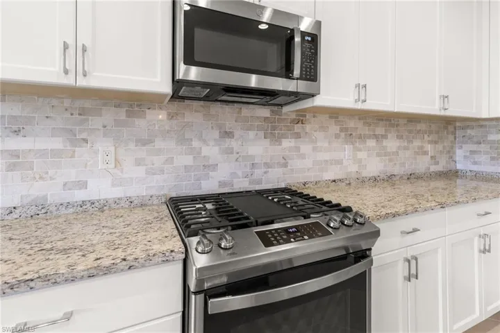 Kitchen featuring white cabinets, backsplash, and appliances with stainless steel finishes