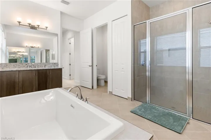 Full bathroom featuring tile patterned flooring, separate shower and tub, vanity, and toilet