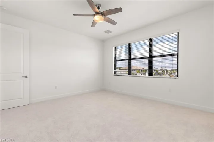 Carpeted spare room featuring ceiling fan