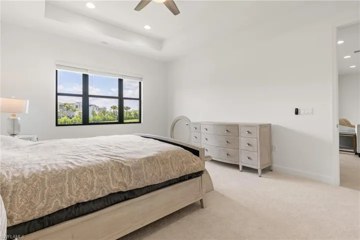 Carpeted bedroom with ceiling fan and a raised ceiling