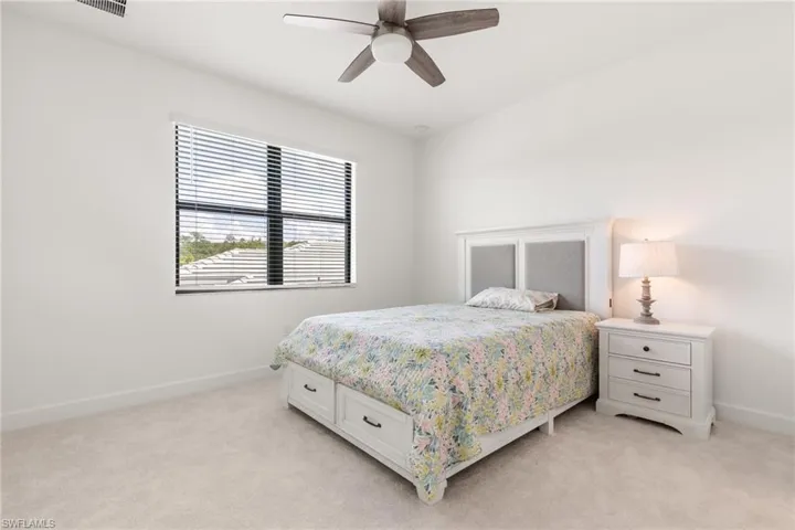 Bedroom with ceiling fan and light carpet