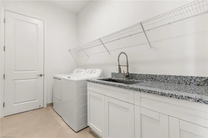 Laundry room featuring washer and dryer, sink, light tile patterned flooring, and cabinets