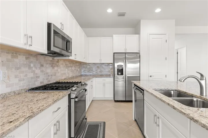 Kitchen featuring sink, white cabinets, appliances with stainless steel finishes, and light tile patterned floors