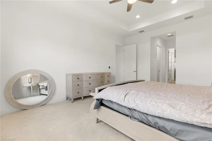 Carpeted bedroom with a tray ceiling and ceiling fan