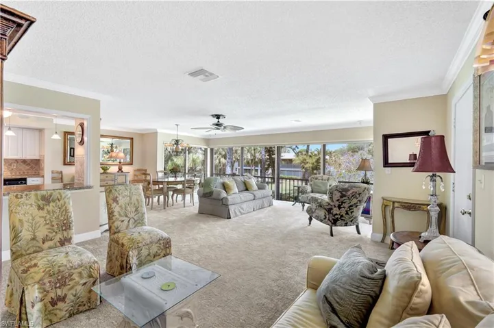 Living area with carpet flooring, a textured ceiling, crown molding, and ceiling fan