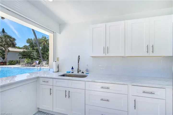 Pool Clubhouse Kitchen with white cabinetry, light stone countertops, and decorative backsplash