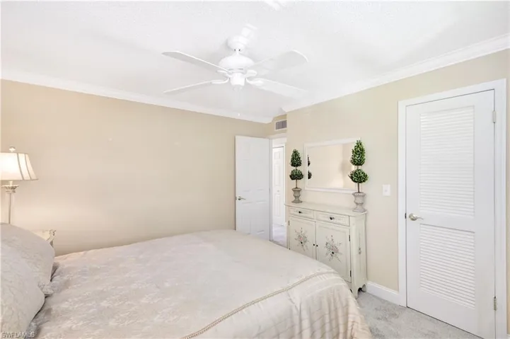 Bedroom with light colored carpet, ornamental molding, ceiling fan, and a textured ceiling