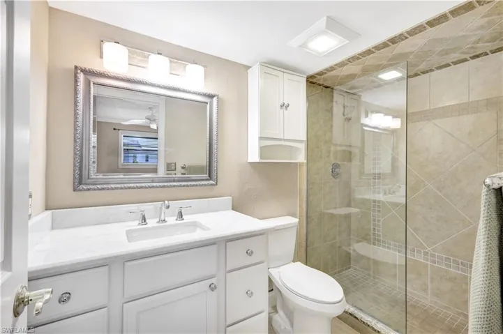 Bathroom with vanity, a shower stall, and a textured wall