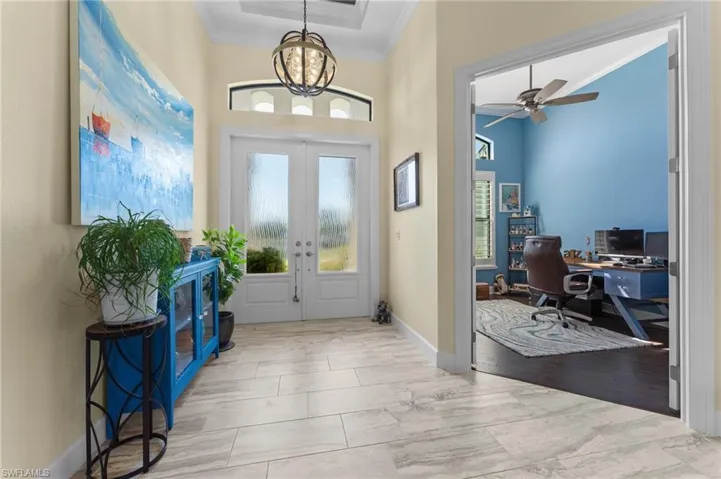 Foyer featuring crown molding, an inviting chandelier, and french doors opening to the Study