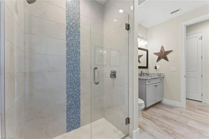 Bathroom 2 with vanity, toilet, an enclosed shower, and upgraded porcelain flooring.