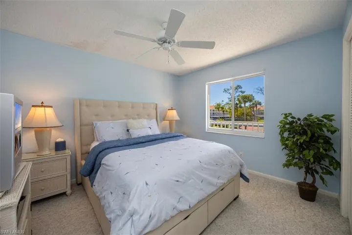 Bedroom with ceiling fan, baseboards, light colored carpet, and a textured ceiling