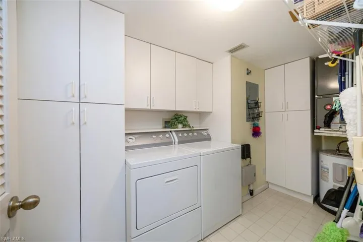 Clothes washing area featuring light tile patterned floors, cabinet space, visible vents, and washer and dryer