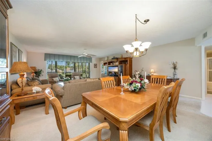 Dining area featuring a chandelier, light carpet, a textured ceiling, baseboards, and visible vents