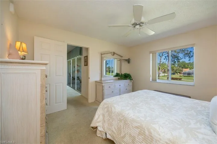 Bedroom featuring a ceiling fan, light colored carpet, and a textured ceiling