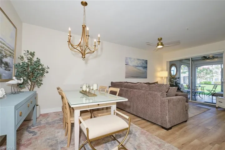 Dining room with ceiling fan with notable chandelier and light hardwood / wood-style flooring