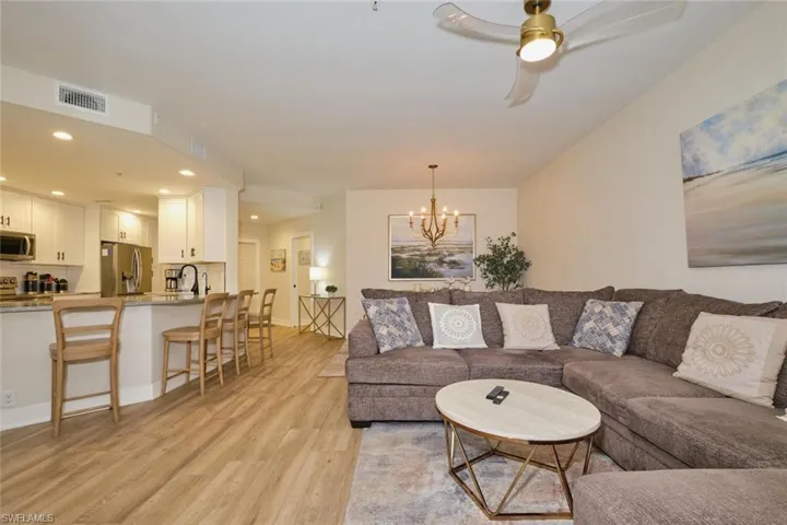 Living room with ceiling fan with notable chandelier and light hardwood / wood-style flooring