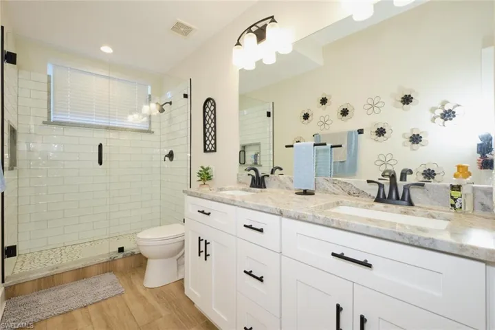 Bathroom featuring hardwood / wood-style flooring, vanity, toilet, and a shower with shower door