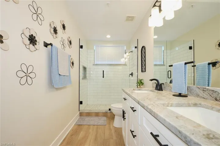 Bathroom with hardwood / wood-style flooring, vanity, a shower with shower door, and toilet