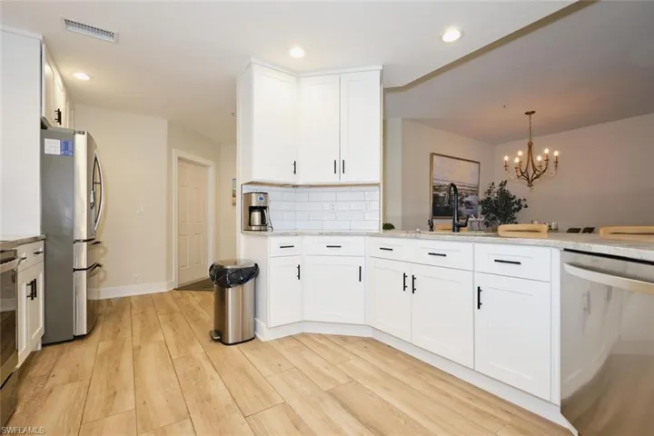 Kitchen with light hardwood / wood-style flooring, stainless steel appliances, white cabinetry, and pendant lighting