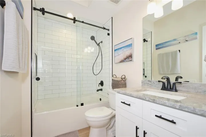 Full bathroom with toilet, vanity, and shower / bath combination with glass door