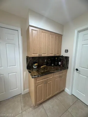 Kitchen with dark stone counters, decorative backsplash, and light tile patterned floors