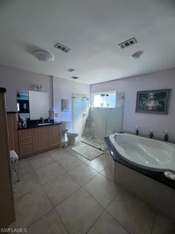 Full bathroom featuring vanity, shower with separate bathtub, toilet, and tile patterned floors