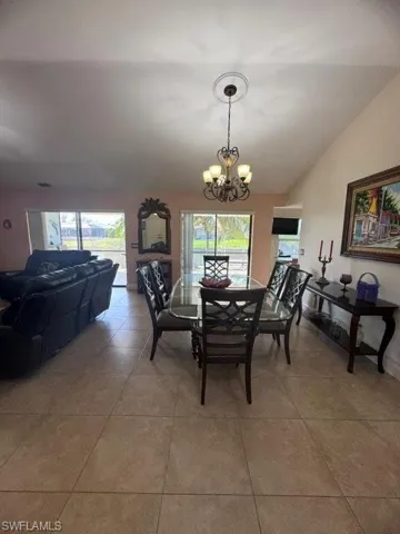 Dining area with a chandelier, light tile patterned floors, and a healthy amount of sunlight