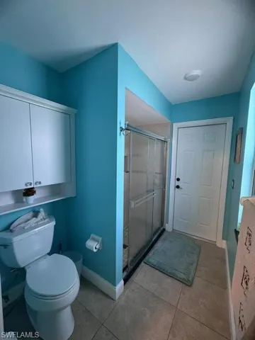 Bathroom with walk in shower, tile patterned floors, and toilet