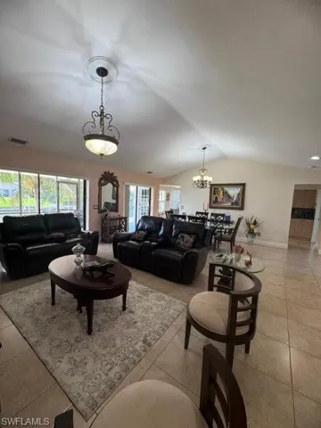 Living room featuring an inviting chandelier, vaulted ceiling, and light tile patterned flooring
