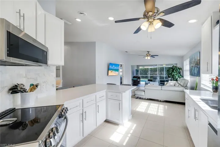 Kitchen featuring stainless steel appliances, a peninsula, white cabinets, recessed lighting, and vaulted ceiling
