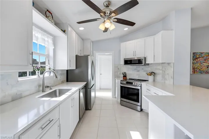 Kitchen with stainless steel appliances, white cabinets, tasteful backsplash, ceiling fan, and a peninsula