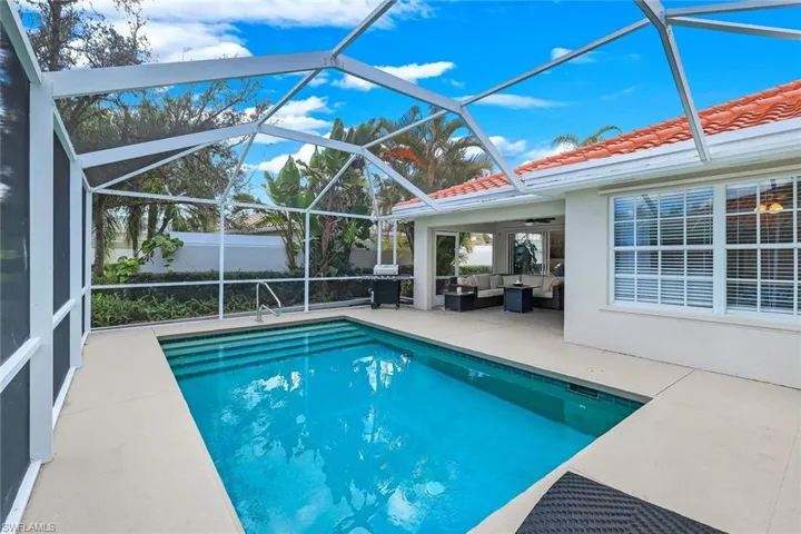 Outdoor pool with outdoor furniture, a sunroom, a patio, area for grilling, and glass enclosure