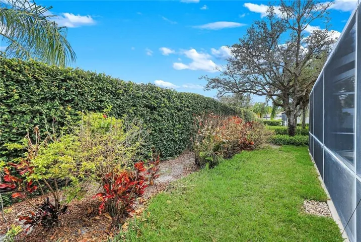 View of green lawn featuring a sunroom and a lanai