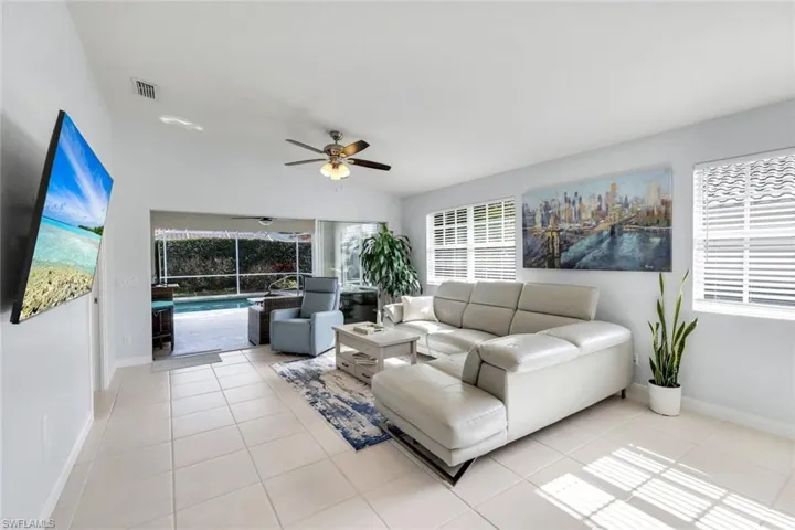 Living room with ceiling fan, lofted ceiling, light tile patterned floors, and a sunroom