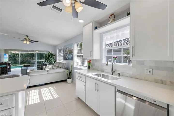 Kitchen featuring a ceiling fan, white cabinetry, stainless steel dishwasher, light tile patterned floors, and vaulted ceiling