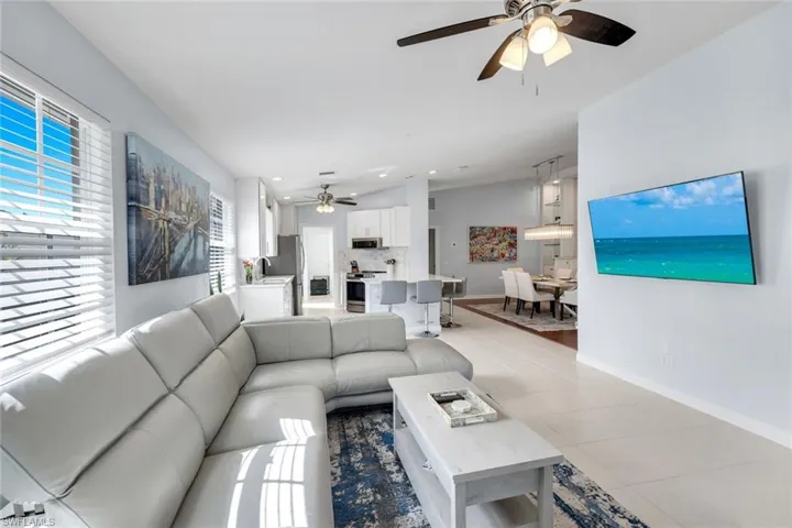 Living area with ceiling fan, light tile patterned floors, vaulted ceiling, and recessed lighting
